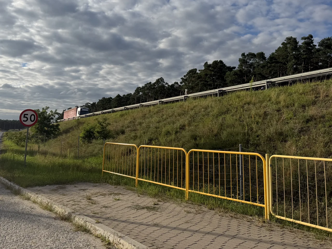 Ulica Toruńska w Cielu wzdłuż nasypu drogi ekspresowej — chodnik, barierki i skarpa z ekranem